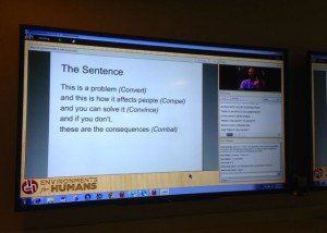 Slide displayed on large monitor on wall.
